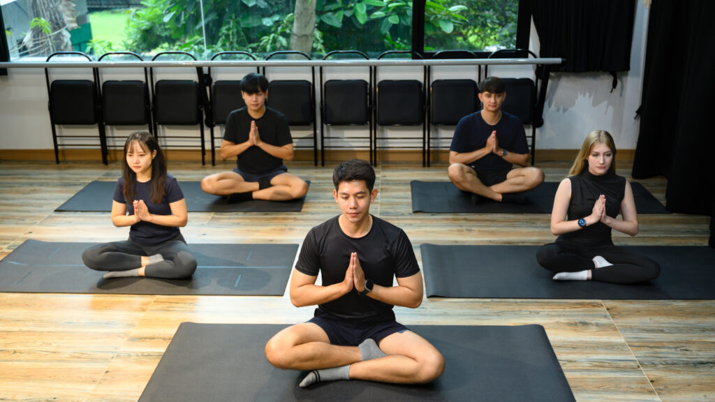 People in meditation posture during group yoga class management program